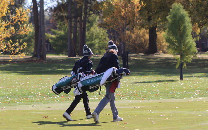 boys holding golf bags walking